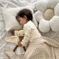 Schlafendes Kleinkind in nachhaltiger Bio-Babymode von Elsara mit Kuscheltier und Blütenkissen